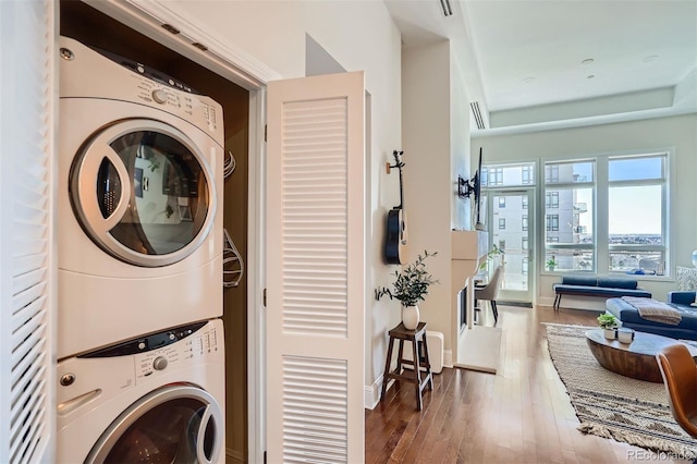 laundry area featuring stacked washer and dryer and hardwood / wood-style flooring