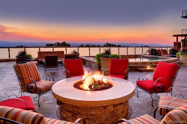 patio terrace at dusk with a fire pit and a water view