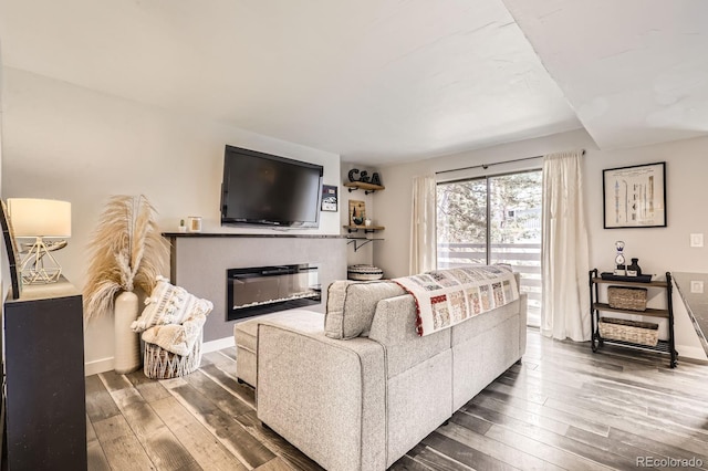 living room with hardwood / wood-style flooring, baseboards, and a glass covered fireplace