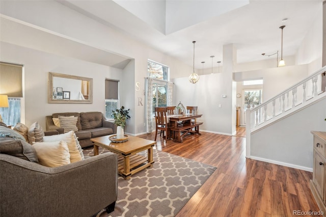 living area with stairway, baseboards, and wood finished floors