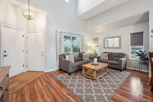 living room featuring a notable chandelier, baseboards, and wood finished floors