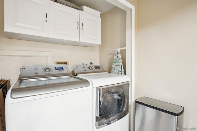 clothes washing area featuring separate washer and dryer and cabinet space