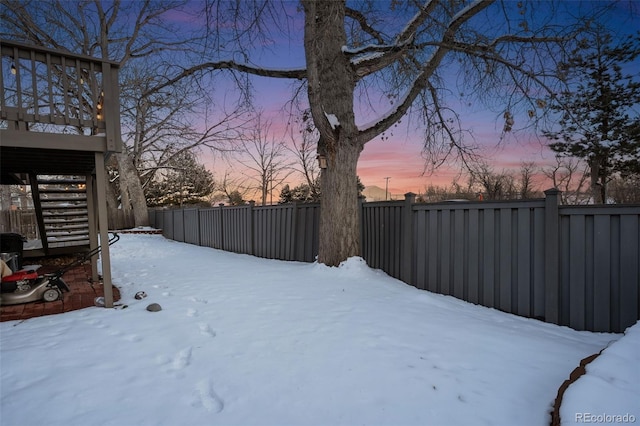 snowy yard with a fenced backyard and stairs