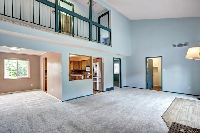 7300 Beech St, Arvada, CO 80005 - unfurnished living room with healthy amount of natural light, a towering ceiling, light colored carpet, and baseboards