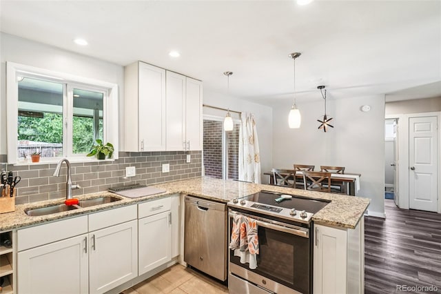 4715 Garland St, Wheat Ridge, CO 80033 - kitchen featuring appliances with stainless steel finishes, a peninsula, decorative backsplash, white cabinets, and recessed lighting