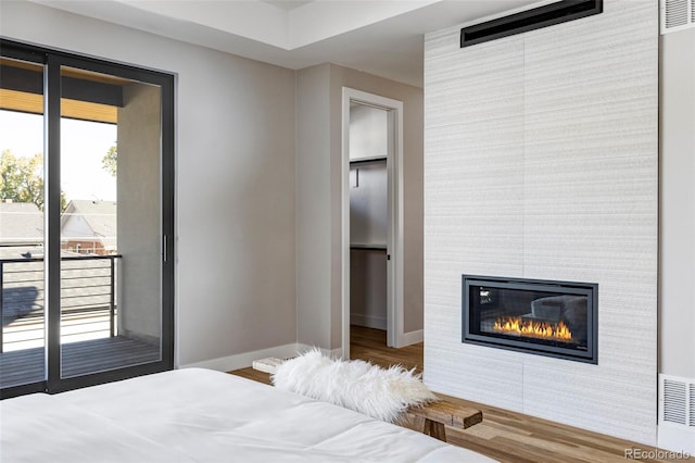 bedroom featuring access to outside, a fireplace, a closet, and hardwood / wood-style floors