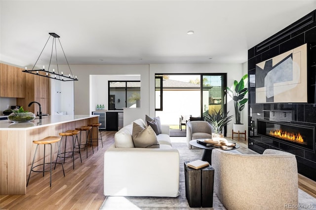 living room featuring a tile fireplace, hardwood / wood-style floors, and sink