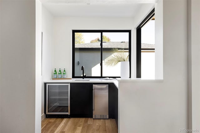 bar with light hardwood / wood-style floors, wine cooler, and sink