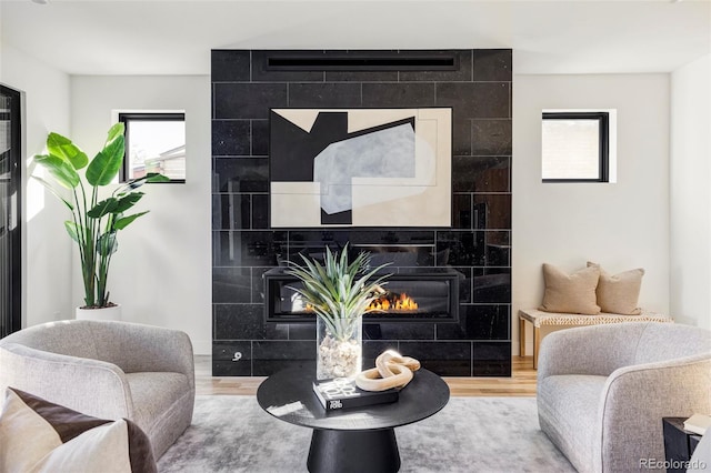 living room with wood-type flooring, tile walls, and a tiled fireplace