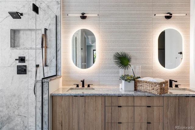 bathroom featuring a tile shower, vanity, and tile walls