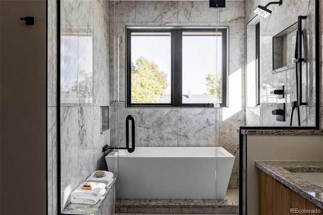 bathroom with vanity, a tub, and tile walls