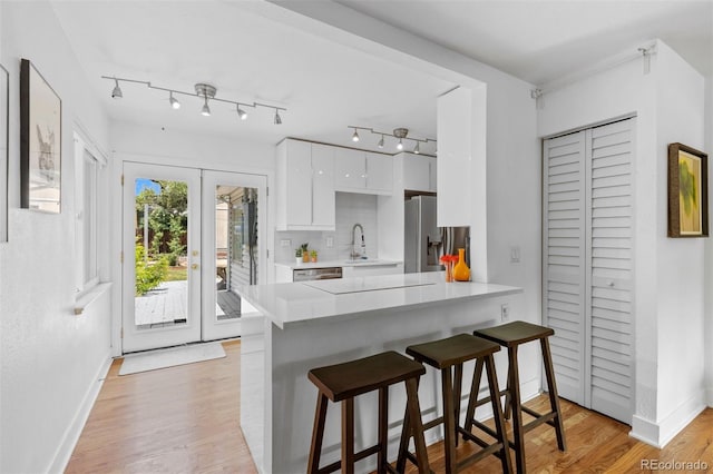 3209 E Yale Way, Denver, CO 80210 - kitchen featuring white cabinetry, light countertops, a breakfast bar area, modern cabinets, and a peninsula