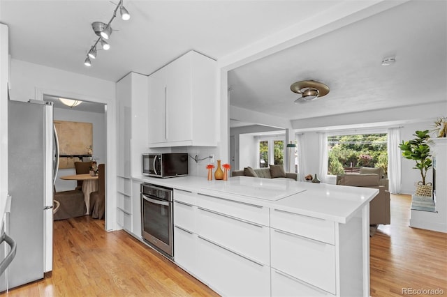 3209 E Yale Way, Denver, CO 80210 - kitchen featuring stainless steel appliances, a peninsula, light wood-style flooring, and modern cabinets