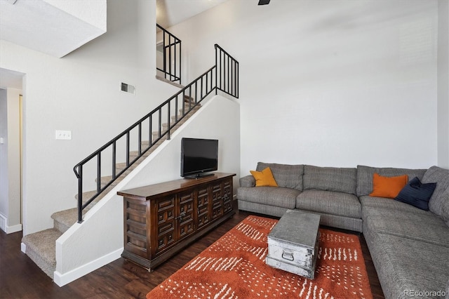 living room with visible vents, a high ceiling, wood finished floors, baseboards, and stairs