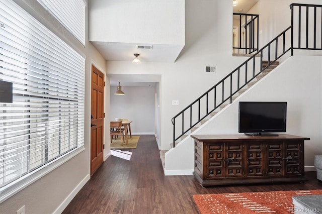 foyer with visible vents, a high ceiling, wood finished floors, baseboards, and stairs