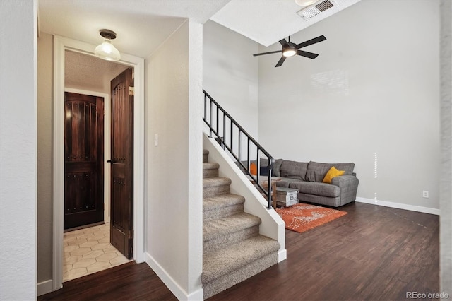 stairway featuring a ceiling fan, baseboards, visible vents, and wood finished floors