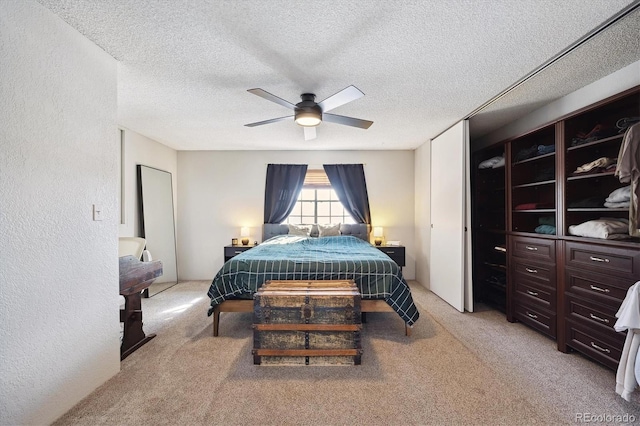 bedroom with a textured ceiling, a textured wall, and light colored carpet