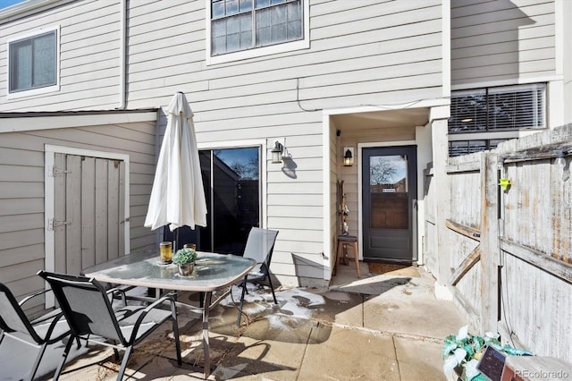 property entrance featuring outdoor dining area, a patio area, and fence