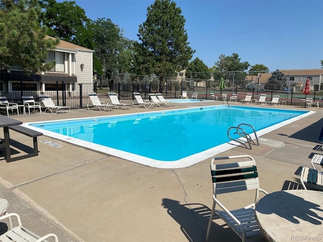 pool with a patio area and fence