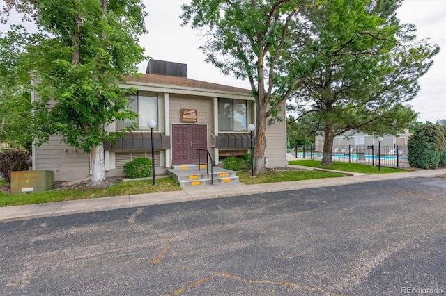 view of front of home with fence and a community pool