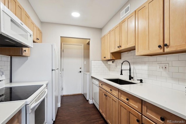 kitchen with a sink, dark wood-type flooring, visible vents, white appliances, and decorative backsplash