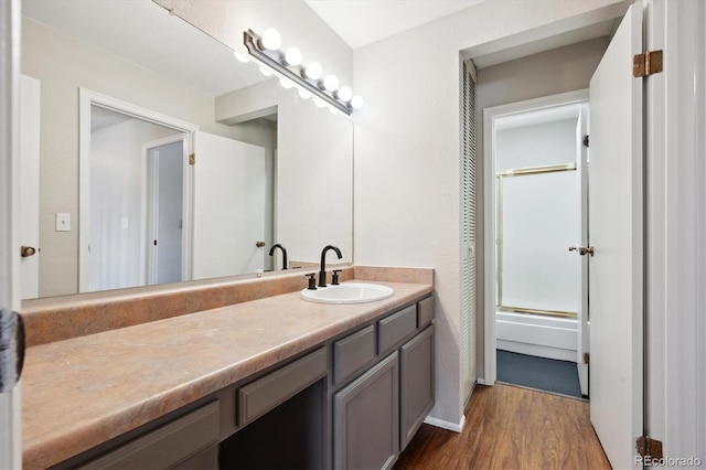 full bath with vanity, shower / bath combination with glass door, and wood finished floors