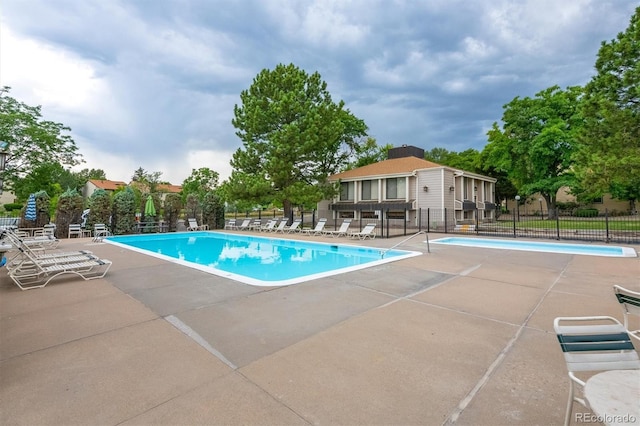 community pool with a patio and fence