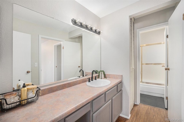 7705 W 87th Dr, Arvada, CO 80005 - full bath with wood finished floors, vanity, and combined bath / shower with glass door