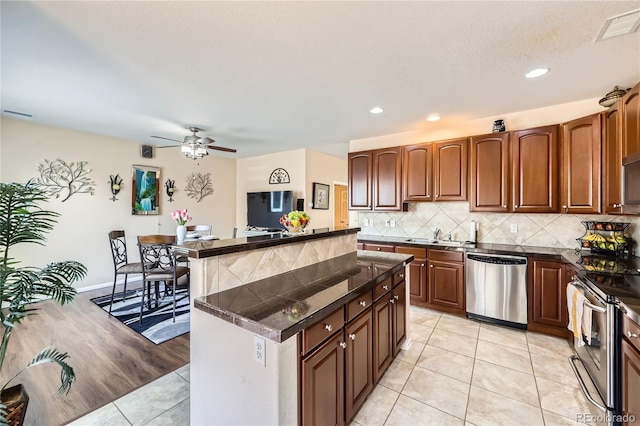 13626 Garfield St Unit A, Thornton, CO 80602 - kitchen featuring appliances with stainless steel finishes, a center island, light tile patterned flooring, dark countertops, and tasteful backsplash