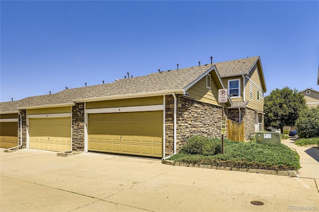13626 Garfield St Unit A, Thornton, CO 80602 - view of front facade featuring stone siding, concrete driveway, a garage, and a shingled roof