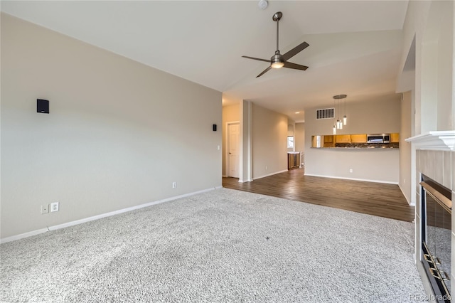 unfurnished living room featuring a tile fireplace, ceiling fan, dark hardwood / wood-style flooring, and lofted ceiling