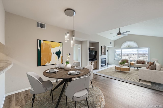 dining room with ceiling fan, wood-type flooring, and lofted ceiling