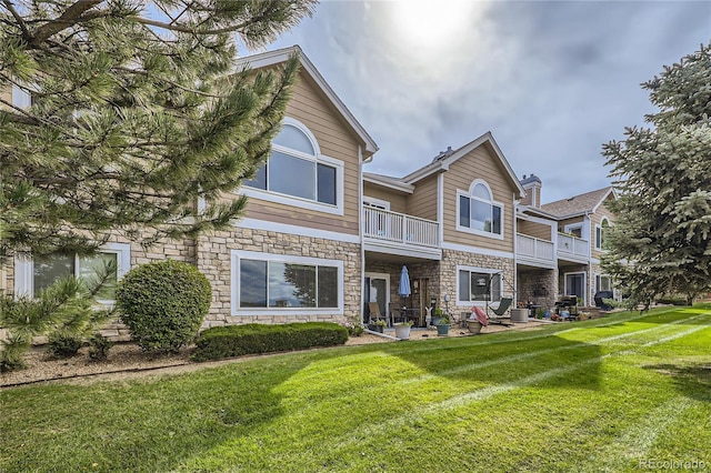 view of front of property featuring a patio area, a balcony, and a front lawn