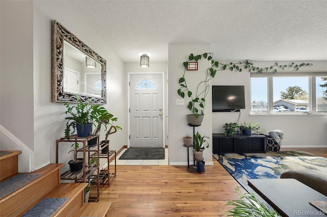 living room with a textured ceiling, light wood-type flooring, and a healthy amount of sunlight