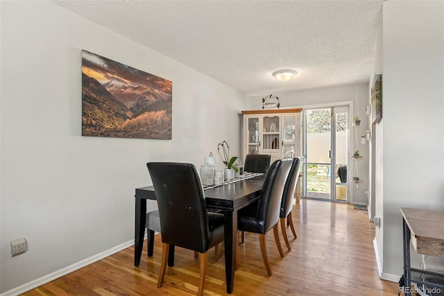 dining space featuring baseboards, wood finished floors, and a textured ceiling