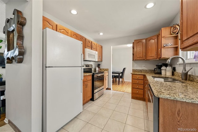 kitchen with recessed lighting, light stone counters, stainless steel appliances, a sink, and light tile patterned flooring