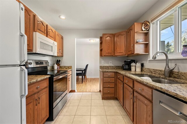 kitchen featuring open shelves, a sink, light tile patterned floors, appliances with stainless steel finishes, and light stone countertops