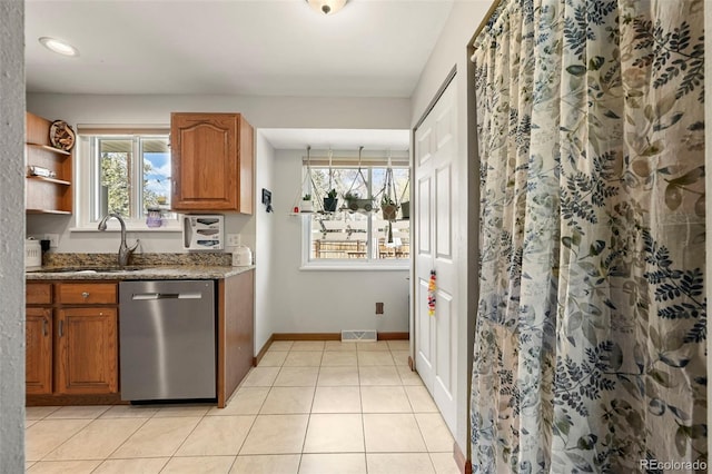 kitchen with stainless steel dishwasher, a sink, visible vents, stone countertops, and brown cabinetry