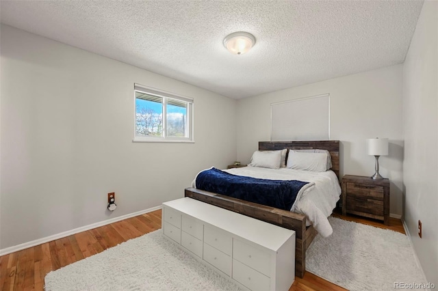 bedroom with light wood-type flooring, a textured ceiling, and baseboards