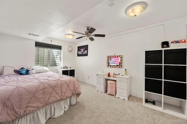 bedroom with a textured ceiling, visible vents, light colored carpet, and ceiling fan