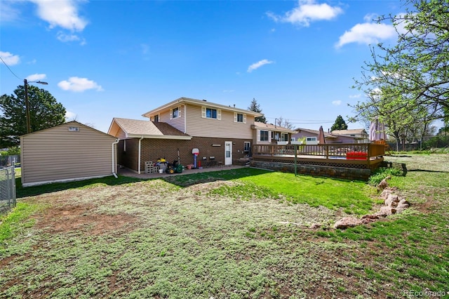 rear view of property featuring a storage shed, a lawn, fence, an outbuilding, and a wooden deck
