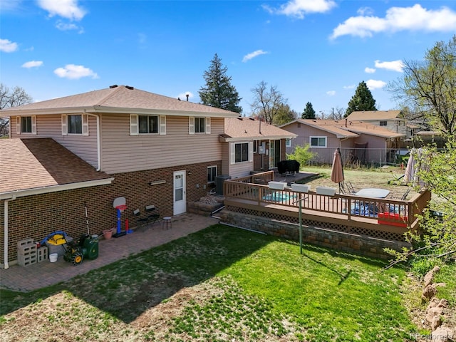 back of house featuring fence, a patio area, a lawn, brick siding, and a deck