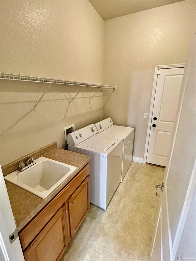 clothes washing area featuring washer and clothes dryer, sink, and cabinets