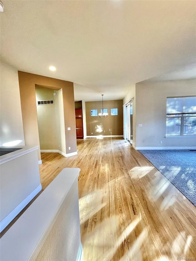 unfurnished living room featuring an inviting chandelier, a textured ceiling, and hardwood / wood-style flooring