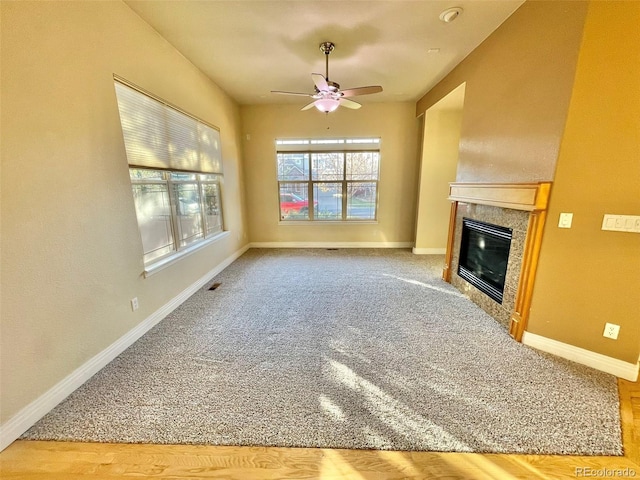 unfurnished living room with a tile fireplace, hardwood / wood-style floors, and ceiling fan