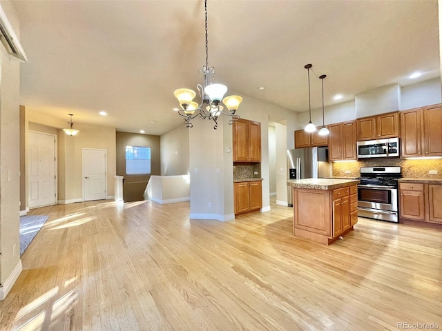 kitchen featuring a center island, light wood-type flooring, hanging light fixtures, and appliances with stainless steel finishes