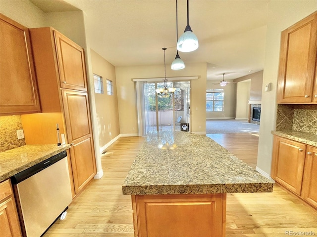 kitchen featuring light wood-type flooring, backsplash, decorative light fixtures, dishwasher, and a center island