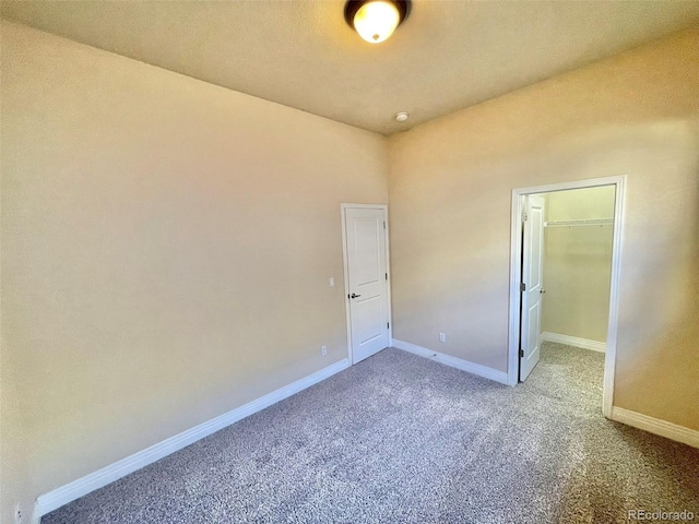 unfurnished bedroom with carpet flooring, a spacious closet, and a closet