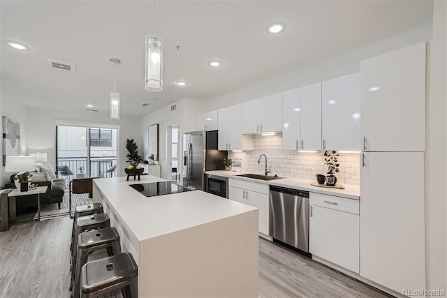 3500 S Corona St Unit 407, Englewood, CO 80113 - kitchen featuring appliances with stainless steel finishes, a sink, a breakfast bar area, a kitchen island, and white cabinets