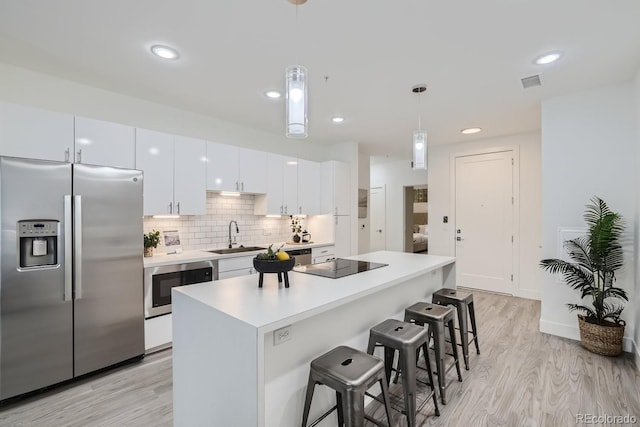 3500 S Corona St Unit 407, Englewood, CO 80113 - kitchen with stainless steel refrigerator with ice dispenser, built in microwave, a breakfast bar, light wood-style floors, and black electric stovetop